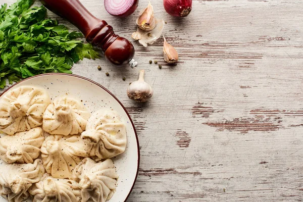 Vue du dessus de délicieux khinkali près des légumes et des épices sur la table en bois — Photo de stock