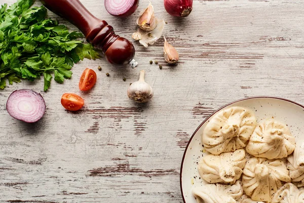 Vista superior de delicioso khinkali cerca de verduras y especias en la mesa de madera - foto de stock