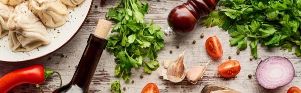 Vista dall'alto di deliziosi khinkali vicino bottiglia di vino, verdure e spezie sul tavolo di legno, colpo panoramico — Foto stock