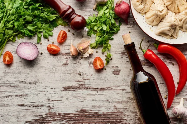 Vista superior de khinkali delicioso perto de garrafa de vinho, legumes e especiarias na mesa de madeira — Fotografia de Stock