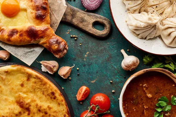 Vista dall'alto di deliziosi khinkali, adiari e imeretian khachapuri, kharcho su sfondo verde — Foto stock