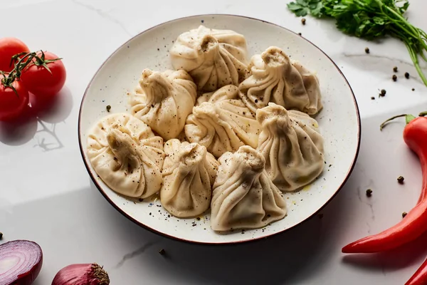 Khinkali delicioso perto de legumes e especiarias na mesa de mármore — Fotografia de Stock