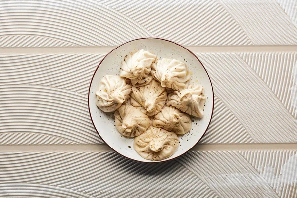 Draufsicht auf frisches, köstliches Chinkali auf texturiertem beigem Hintergrund — Stockfoto