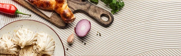 Top view of delicious khinkali and adjarian khachapuri near vegetables and spices on beige textured background, panoramic shot — Stock Photo