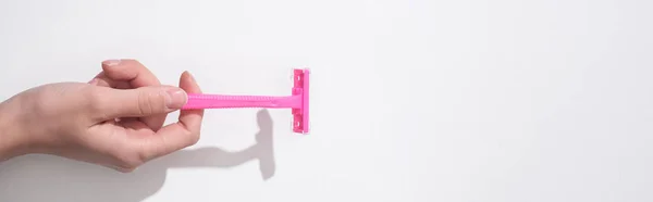 Vista recortada de la mujer sosteniendo la navaja rosa femenina sobre fondo blanco, plano panorámico - foto de stock