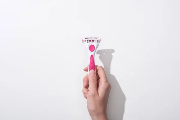 Cropped view of woman holding female pink razor on white background — Stock Photo