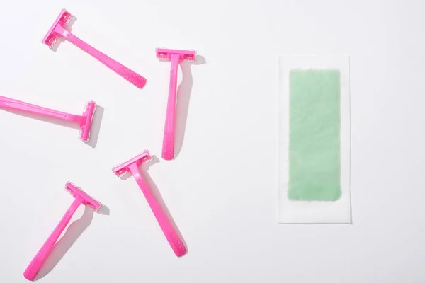 Top view of female pink razors and depilation stripe on white background — Stock Photo