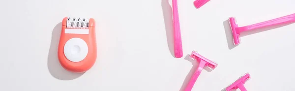 Vista dall'alto di rasoi rosa femminili e epilator su sfondo bianco, colpo panoramico — Foto stock
