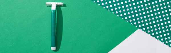 Vista dall'alto del rasoio verde usa e getta su sfondo punteggiato verde e bianco, colpo panoramico — Foto stock