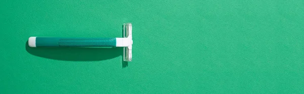 Top view of green disposable razor on green background, panoramic shot — Stock Photo