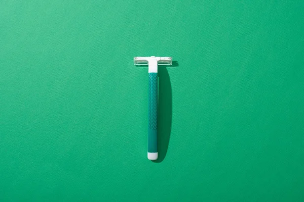 Top view of green disposable razor on green background — Stock Photo