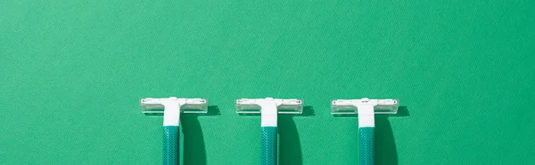 Flat lay with green disposable razors on green background, panoramic shot — Stock Photo