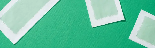 Top view of depilation wax stripes on green background, panoramic shot — Stock Photo
