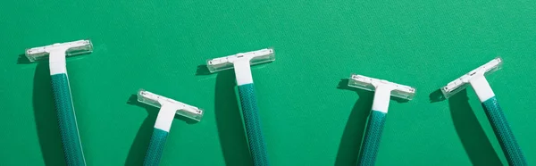 Vista superior de maquinillas de afeitar desechables verdes sobre fondo verde, plano panorámico - foto de stock