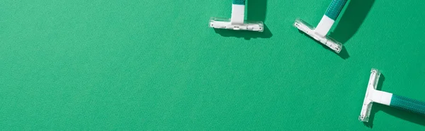 Top view of green disposable razors on green background, panoramic shot — Stock Photo