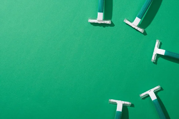 Vista superior de maquinillas de afeitar desechables verdes sobre fondo verde - foto de stock
