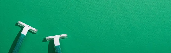 Top view of green disposable razors on green background, panoramic shot — Stock Photo