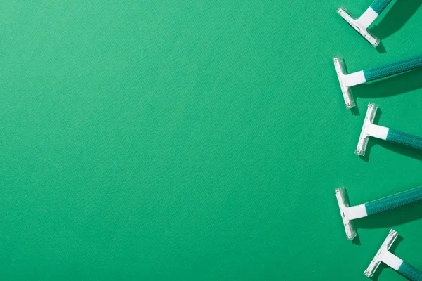 Vue de dessus des rasoirs jetables verts sur fond vert avec espace de copie — Photo de stock