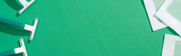 Vista superior de lâminas de barbear descartáveis verdes e listras de cera de depilação no fundo verde com espaço de cópia, tiro panorâmico — Fotografia de Stock