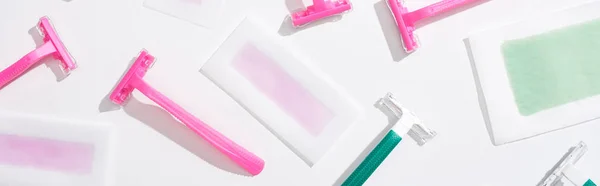 Top view of green and pink razors and depilation wax stripes on white background, panoramic shot — Stock Photo