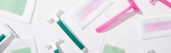 Top view of green and pink razors and depilation wax stripes on white background, panoramic shot — Stock Photo