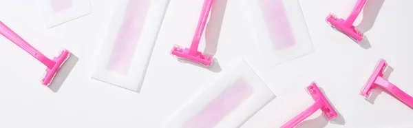 Top view of pink razors and depilation wax stripes on white background, panoramic shot — Stock Photo