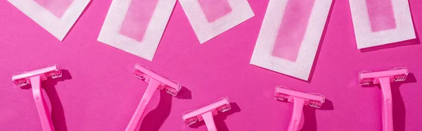 Vista superior de maquinillas de afeitar desechables y rayas de depilación de cera sobre fondo rosa, plano panorámico - foto de stock