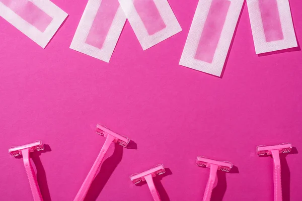 Vista superior de lâminas descartáveis e listras de depilação de cera no fundo rosa — Fotografia de Stock