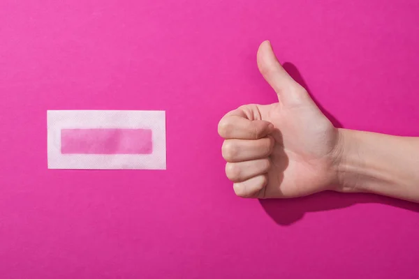 Cropped view of woman showing thumb up near depilation wax stripe on pink background — Stock Photo