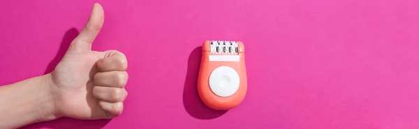 Cropped view of woman showing thumb up near epilator on pink background, panoramic shot — Stock Photo