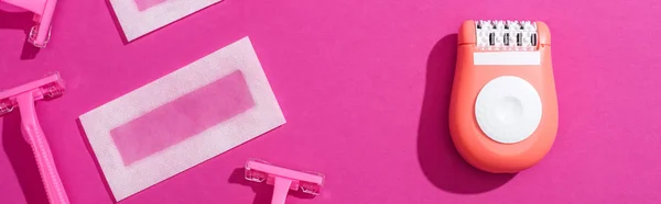 Vista superior de maquinillas de afeitar desechables, depilador y depilación de cera rayas sobre fondo rosa, plano panorámico - foto de stock