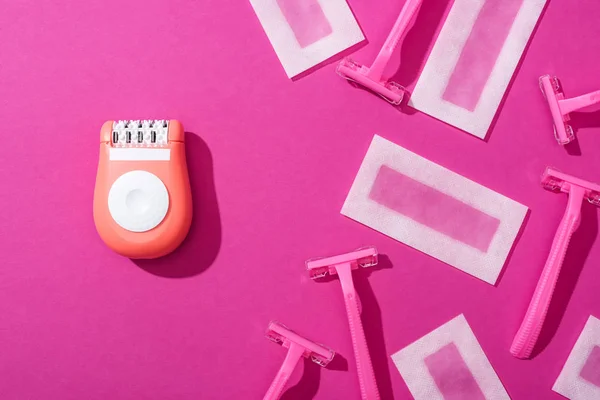 Top view of disposable razors, epilator and wax depilation stripes on pink background — Stock Photo