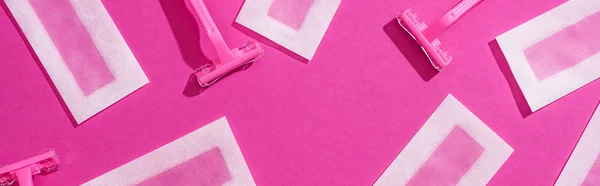 Top view of disposable razors and wax depilation stripes on pink background, panoramic shot — Stock Photo