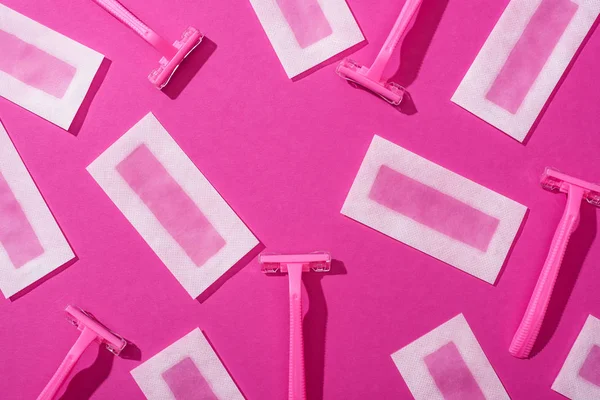 Top view of disposable razors and wax depilation stripes on pink background — Stock Photo