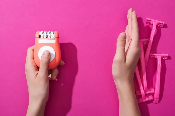 Vista ritagliata di donna che si allontana rasoi usa e getta e prendere epilator su sfondo rosa — Foto stock