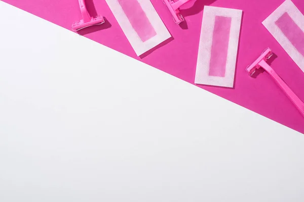 Vista superior de máquinas de afeitar desechables y rayas de depilación de cera sobre fondo blanco y rosa - foto de stock