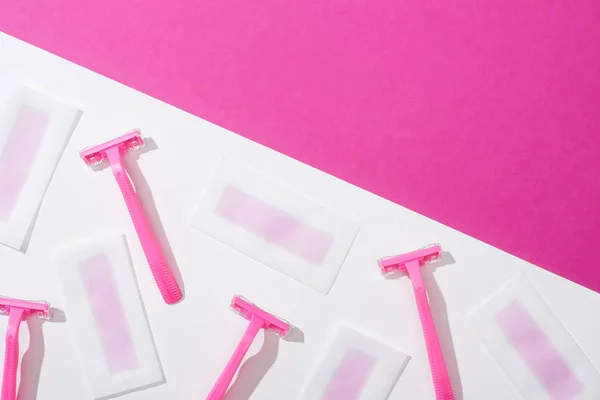 Top view of disposable razors and wax depilation stripes on white and pink background — Stock Photo