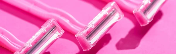 Vista de cerca de las maquinillas de afeitar desechables sobre fondo rosa, plano panorámico - foto de stock