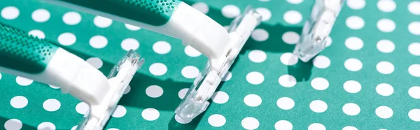 Close up view of disposable razors on green and white dotted background, panoramic shot — Stock Photo