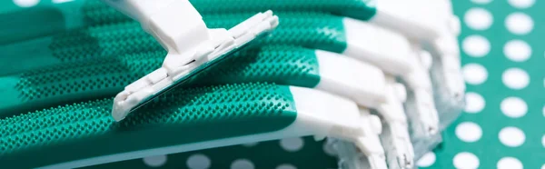 Close up view of disposable razors on green and white dotted background, panoramic shot — Stock Photo