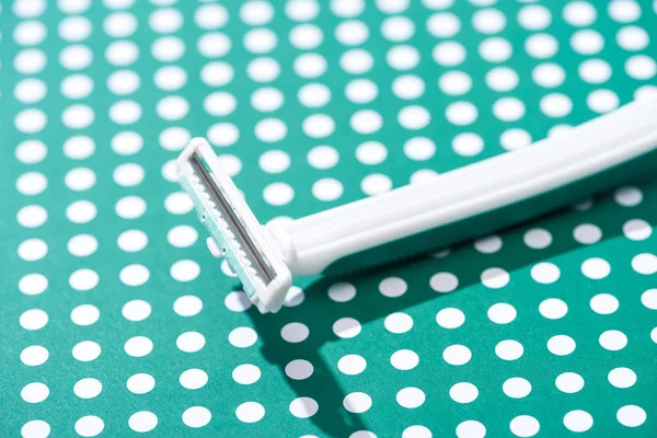 Close up view of disposable razor on green and white dotted background — Stock Photo