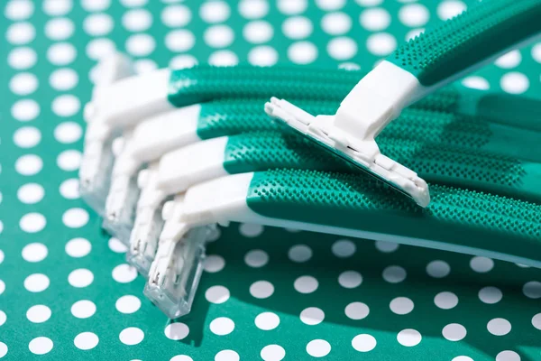 Close up view of disposable razors on green and white dotted background — Stock Photo