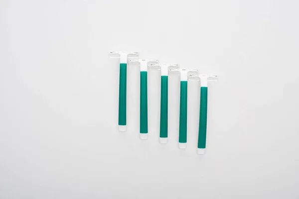 Flat lay with green disposable razors on white background — Stock Photo