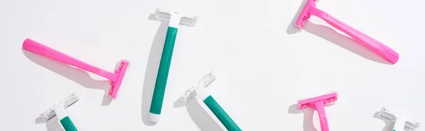 Top view of female pink and green disposable razors on white background, panoramic shot — Stock Photo