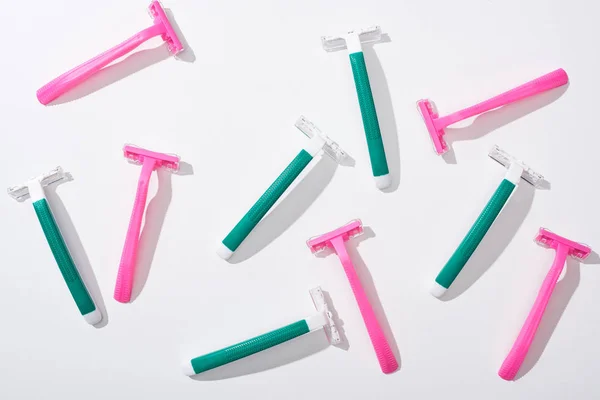 Top view of female pink and green disposable razors on white background — Stock Photo