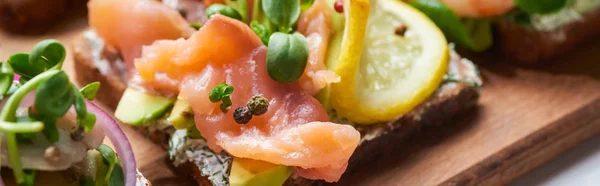 Colpo panoramico di filetto di salmone vicino al limone affettato su gustoso panino allo smorrebrod — Foto stock