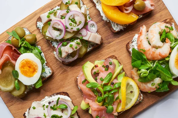 Blick von oben auf köstliche Smorrebrod-Sandwiches auf einem hölzernen Schneidebrett auf Weiß — Stockfoto