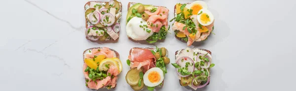Panoramic shot of fresh smorrebrod sandwiches on white marble surface — Stock Photo