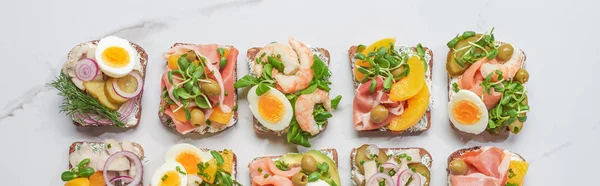 Panoramic shot of fresh and delicious smorrebrod sandwiches on white marble surface — Stock Photo