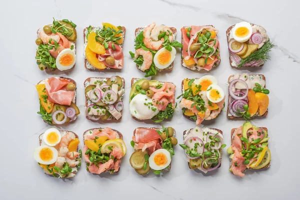 Draufsicht auf dänische Smorrebrod-Sandwiches auf weißem Marmor — Stockfoto